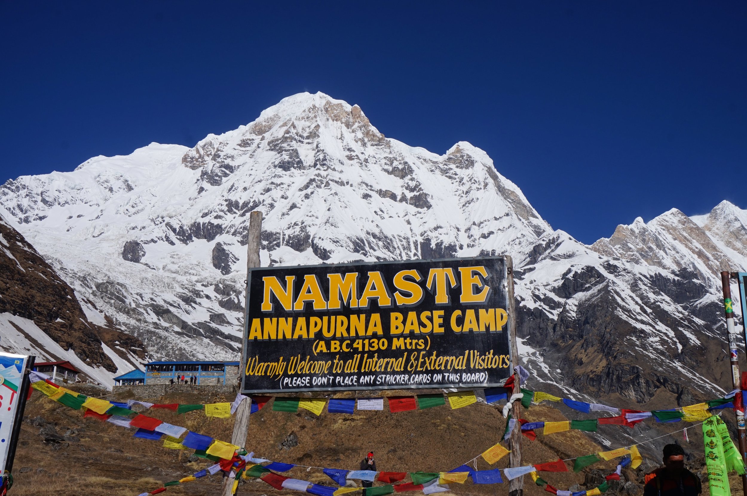 Annapurna Base Camp Sign at 4,130 meters with mountain peak behind