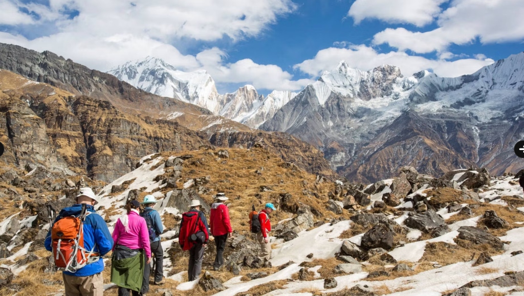 Trekkers walking on a trail with giant snow peaks in the background